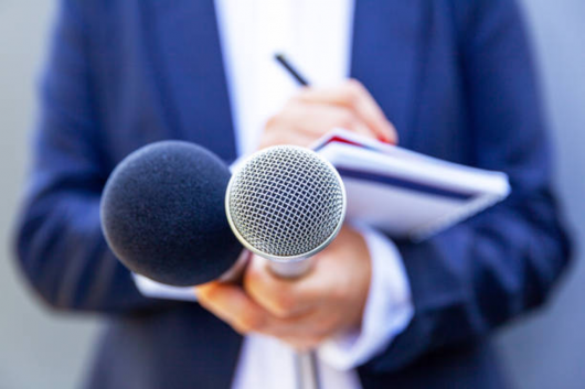 Close-up of a person holding two microphones and a notepad